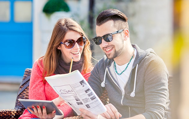 A man and woman looking at homes for sale in a magazine