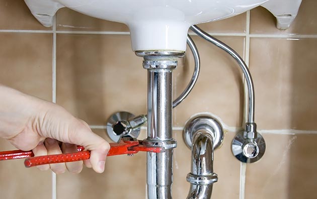 Person fixing pipes under sink