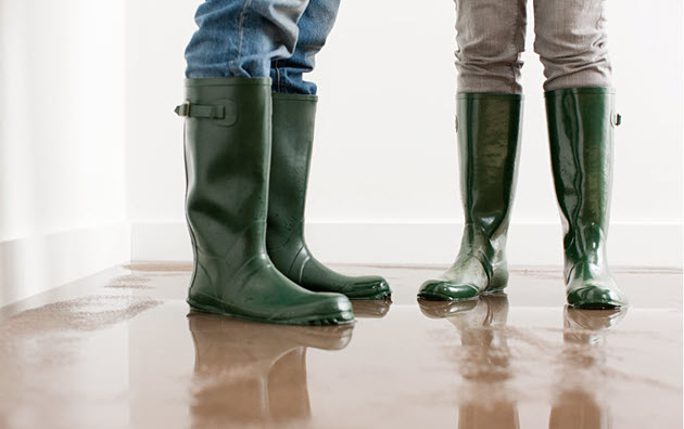 two people standing in rain boots in flooded room