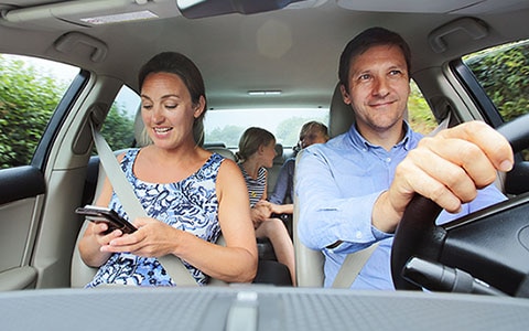 Family in car, mother looking at phone