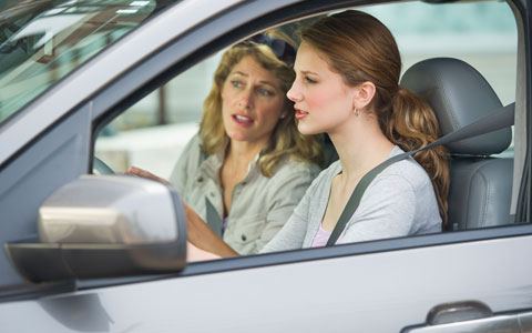 Mother talking teenage daughter through driving on the road