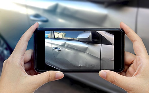 Person holding a smartphone to take photo of car after an accident