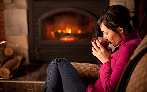 Woman sitting by fireplace