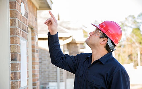 Home inspector pointing his finger and inspecting the roof of a house