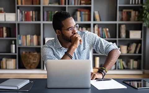 man sitting at a desk in front of laptop