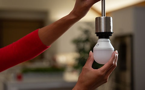 two hands installing a smart light bulb, how to set up smart lighting