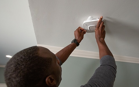 Human installing a smart home smoke dectector