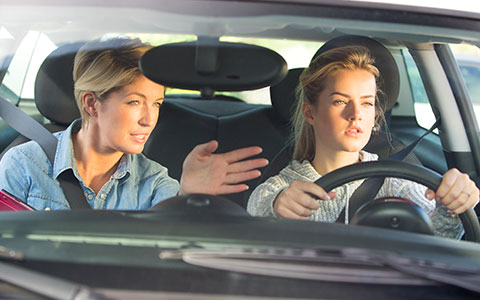 Parent teaching teenager how to drive