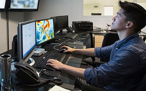 looking at computer screens to monitor and track a storm
