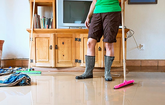 Person with rain boots on cleaning up water 