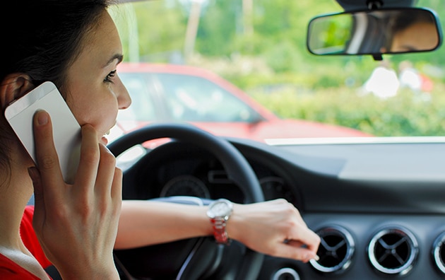 Woman talking on phone behind the wheel of a car