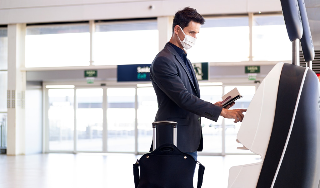 man wearing a face mark at airport with suitcase