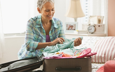 Image of a woman packing a suitcase for a trip. How to Pack a Suitcase for Vacation