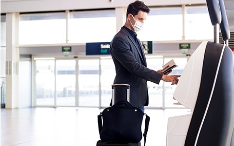 man checking into flight at airport wearing mask