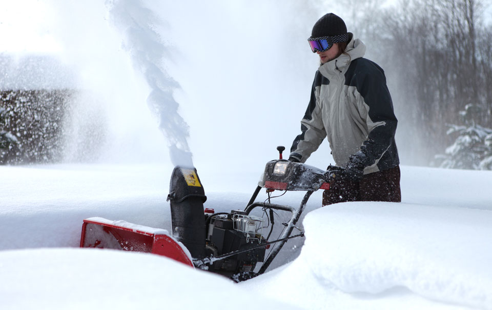 Person using snow blower to remove snow from driveway