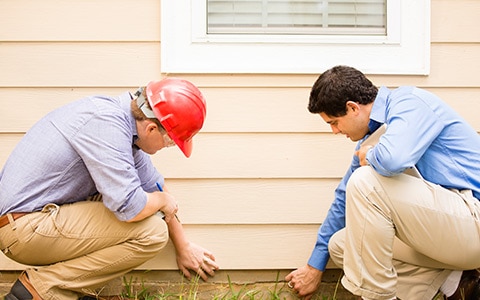 homeowner and inspector looking at house after disaster