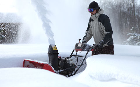 Person using snow blower to remove snow from sidewalk