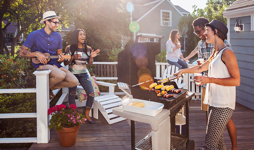 A group of friends outside, enjoying a cookout on the deck of a home