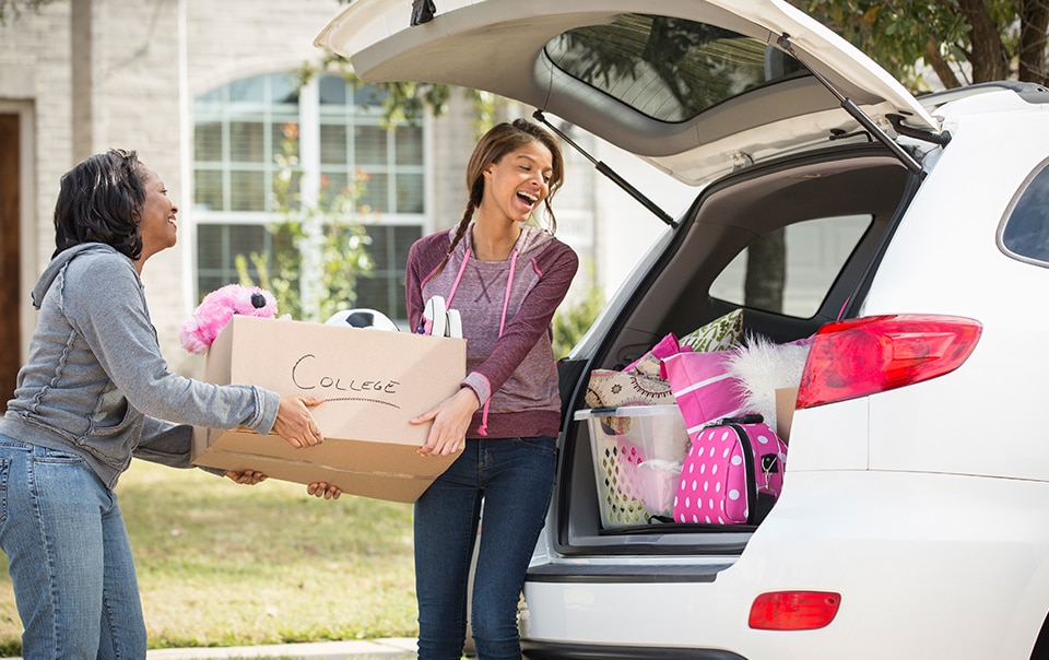 Young woman and her mom packing boxes into a car, heading off to college