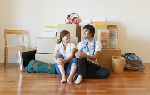 Young happy couple sitting on the floor of their new apartment in front of boxes