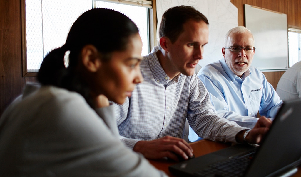 Three employees looking over information on a computer.