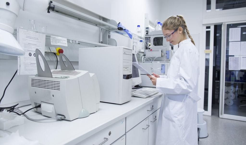 A laboratory scientist is standing tall as she is reviewing paperwork.