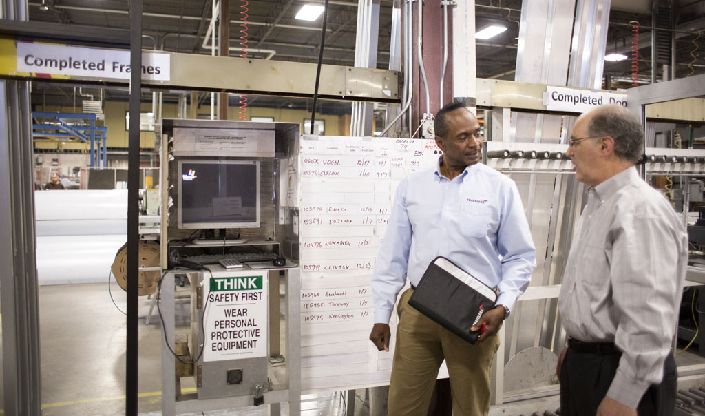 A Travelers employee and another employee are having a conversation as they inspect a manufacturing plant.