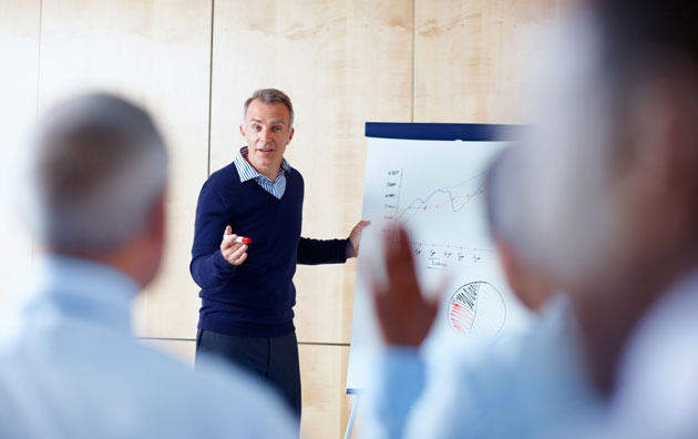 An employee is presenting a graph data set to his coworkers.