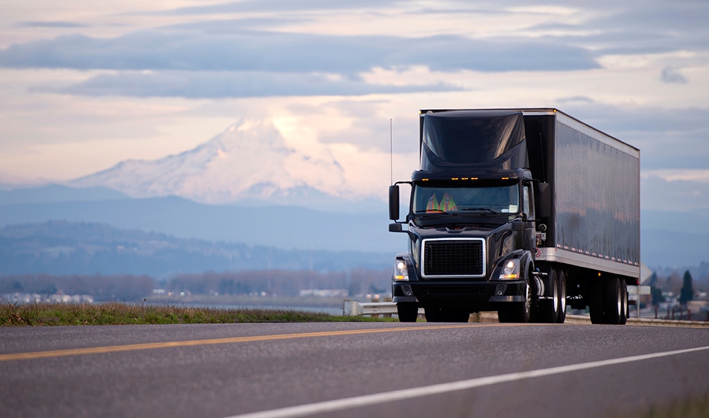 Front view of a black truck driving on the highway.