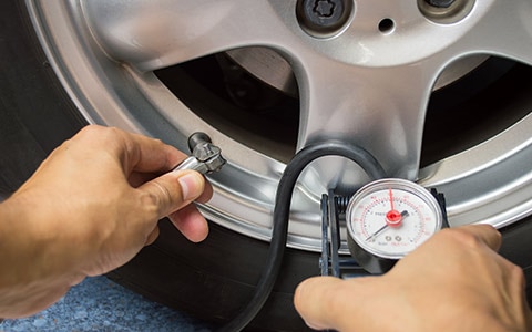 Person checking tire pressure as part of car maintenance