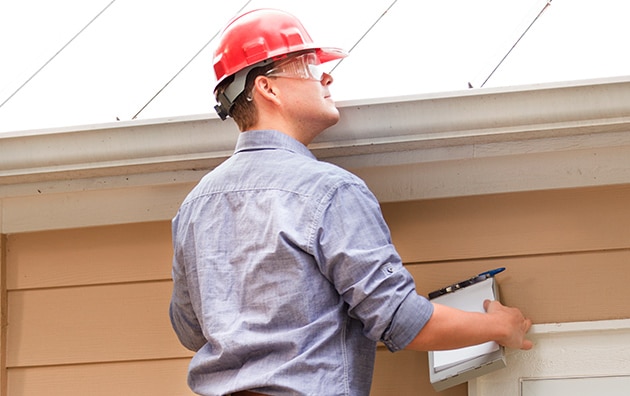 Inspector looking at gutters as part of home inspection checklist