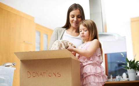 Mother and daughter decluttering house by packing donations