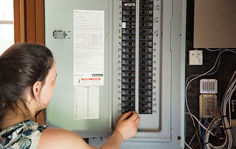 person looking at electrical box in a home