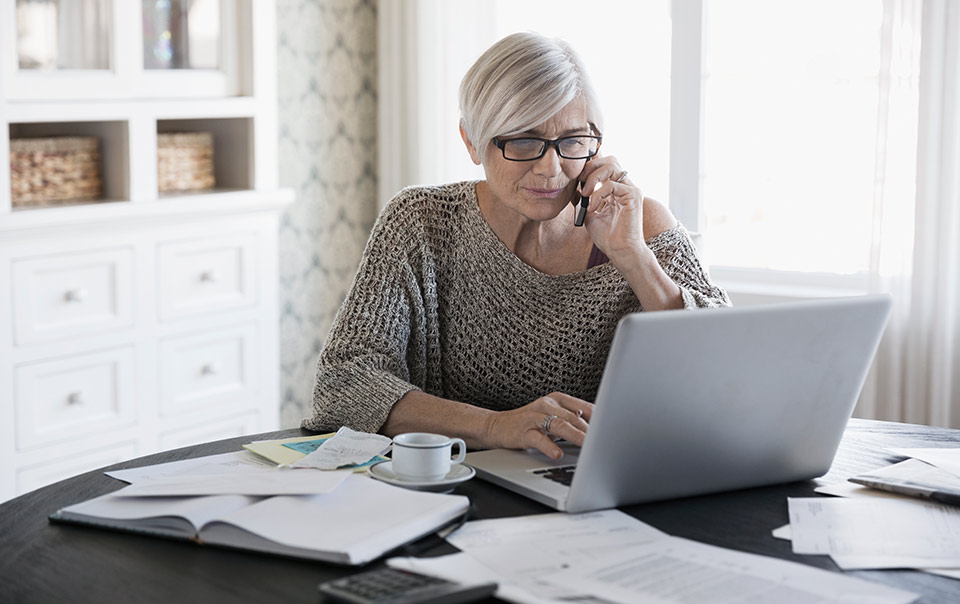 Woman on laptop calling to get a homeowners insurance quote