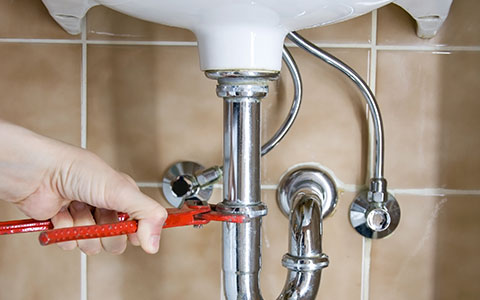 Person tightening sink pipes